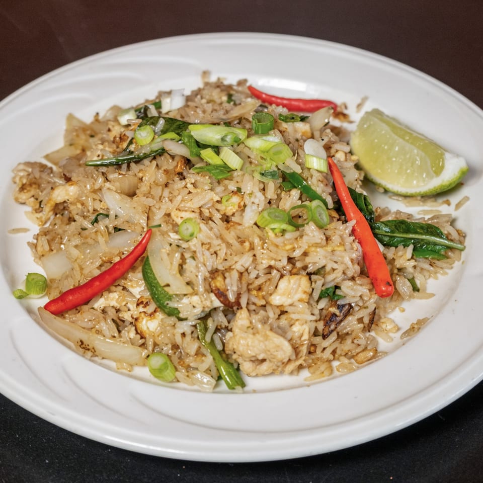 Lily Thai's fried rice with chicken, red chilies, green onions, and a lime wedge on a white plate.