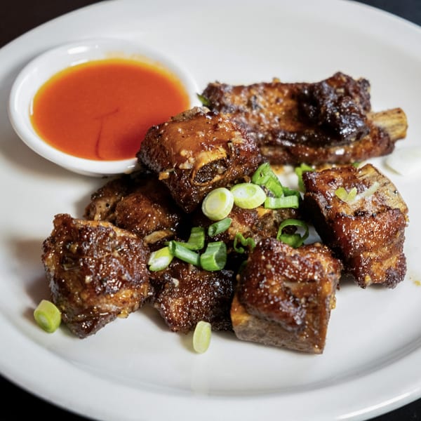 Lily Thai's glazed pork ribs with chopped green onions and a side of sweet chili sauce.