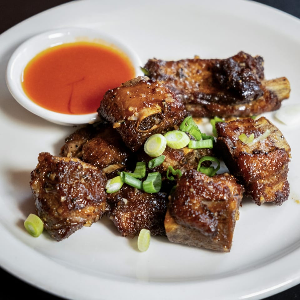 Lily Thai's glazed pork ribs with chopped green onions and a side of sweet chili sauce.